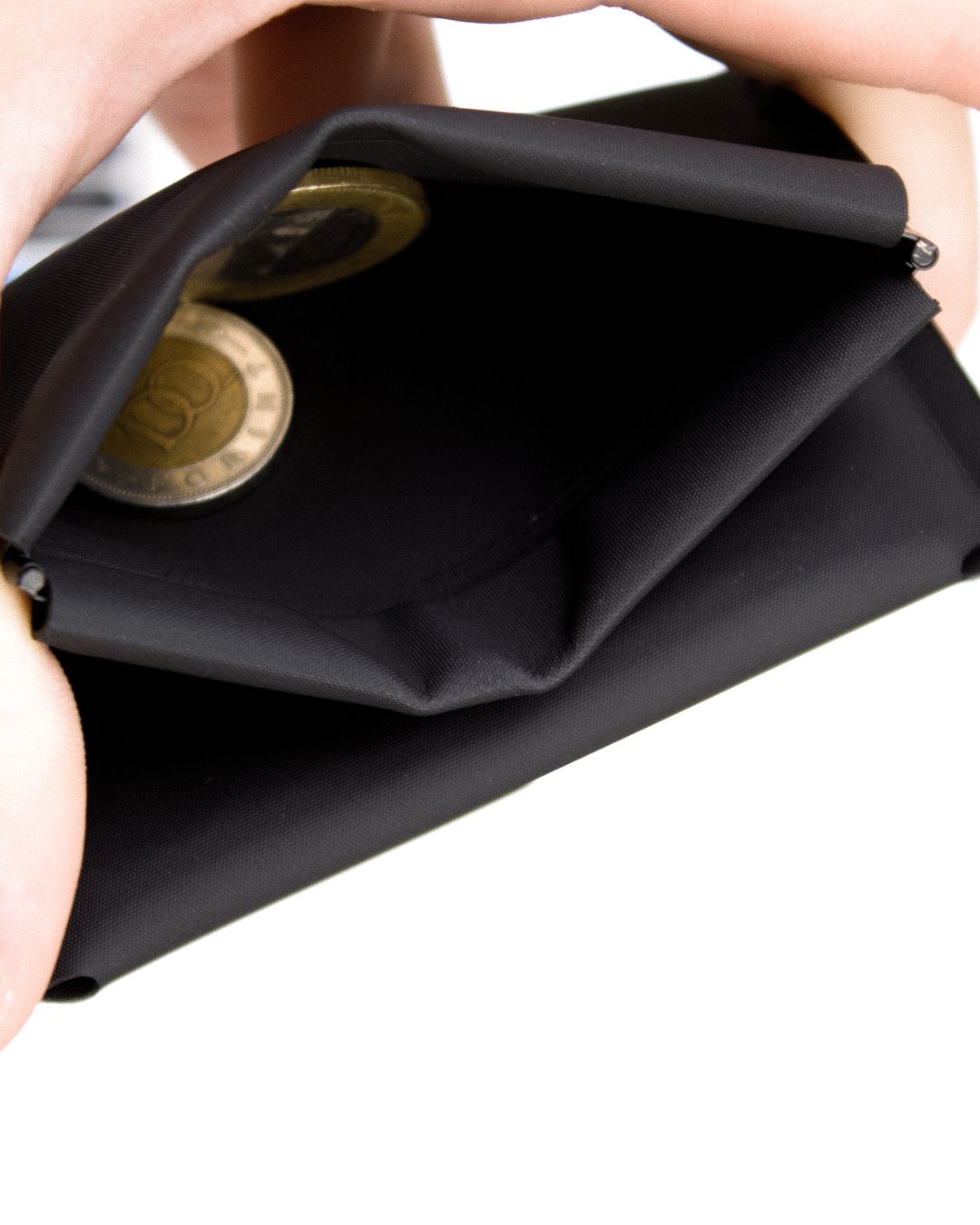 The spring coin pocket held open in two hands, two coins inside
